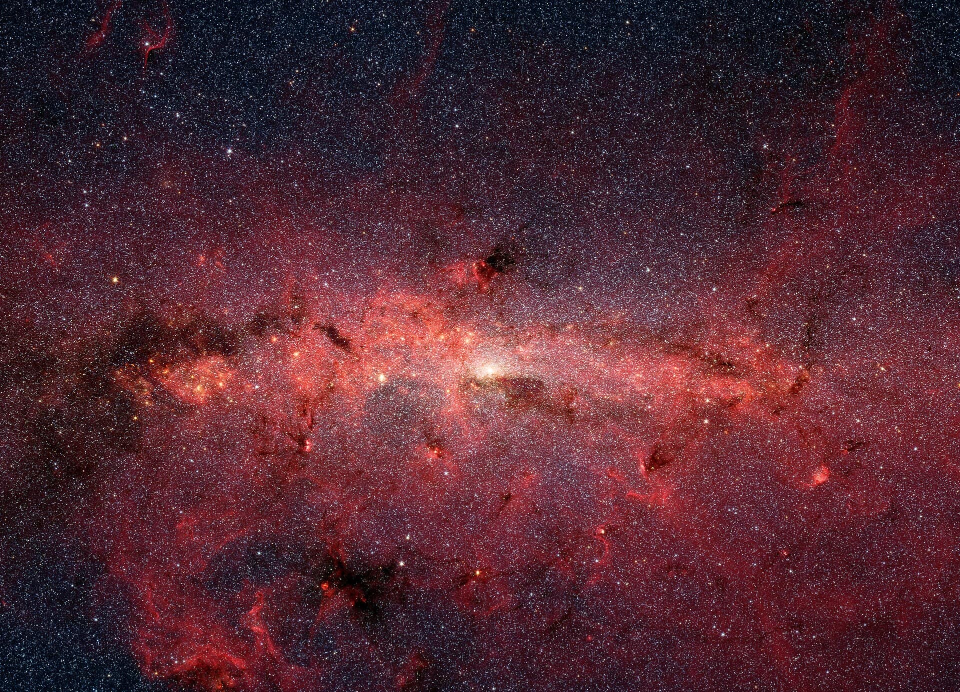 The center of our Milky Way galaxy is hidden from the prying eyes of optical telescopes by clouds of obscuring dust and gas. But in this stunning vista, the Spitzer Space Telescope's infrared cameras penetrate much of the dust, revealing the stars of the crowded galactic center region. The upcoming James Webb Space Telescope will offer a much-improved infrared view, teasing out fainter stars and sharper details. The center of our galaxy is a crowded place: A black hole weighing 4 million times as much as our Sun is surrounded by millions of stars whipping around it at breakneck speeds. This extreme environment is bathed in intense ultraviolet light and X-ray radiation. Yet much of this activity is hidden from our view, obscured by vast swaths of interstellar dust. NASA’s James Webb Space Telescope is designed to view the universe in infrared light, which is invisible to the human eye, but is very important for looking at astronomical objects hidden by dust. After its launch, Webb will gather infrared light that has penetrated the dusty veil, revealing the galactic center in unprecedented detail.